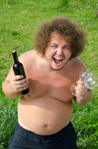 Divertente ragazzo grasso con una bottiglia di vino — Foto Stock