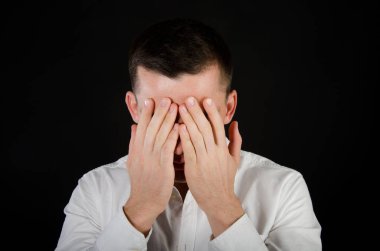 Genç yakışıklı adam elleriyle yüzünü kapsar. İş ve stres. Ofis çalışanı. İş yerinde sorun