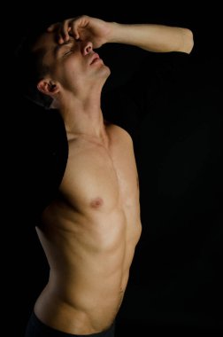 Güzel bir vücudu olan genç seksi adam. Atletik vücut siyah bir arka plan üzerinde poz ile model. Genç çekici adam.