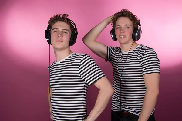 Two attractive guys listening to headphones.