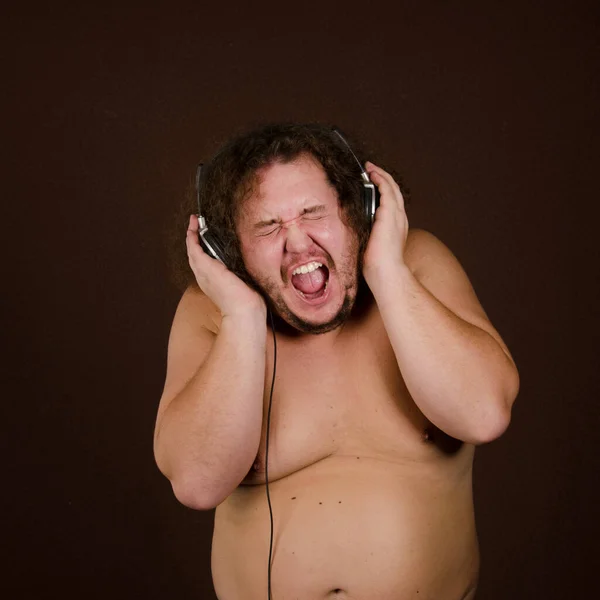 Funny fat guy listens to music on headphones.