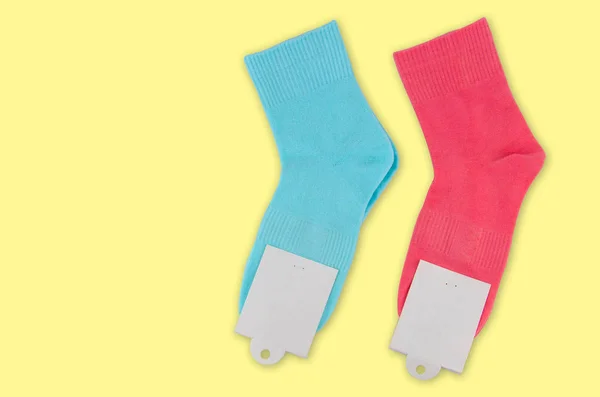 Une nouvelle paire de chaussettes avec une étiquette sur un fond coloré. Chaussettes colorées avec étiquette blanche pour votre design. Objet isolé — Photo