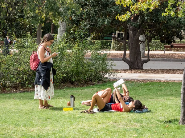 stock image Madrid, Spain, October 9, 2019 . Young students relaxing on laws  in the  park. Three girls  talking on grass.