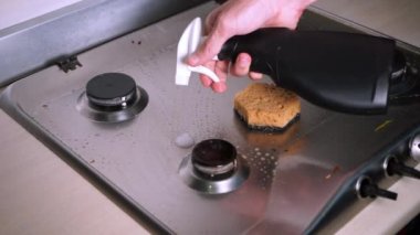 Bir adam gaz sobasının üzerindeki kompleks kirleticileri temizler.