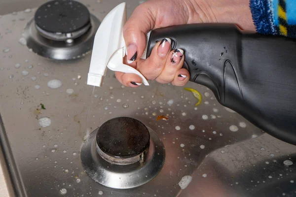 La mano de una mujer maneja la estufa de gas con un removedor de grasa. El concepto de hogar . — Foto de Stock