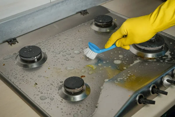 Housewife in yellow protective gloves, washes the gas stove with grease cleanser Royalty Free Stock Photos