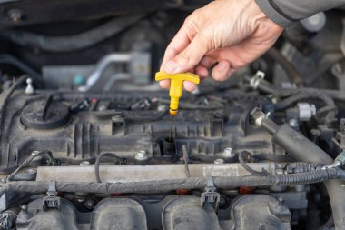 Bir motorcunun elindeki motor yağının dipçiği.