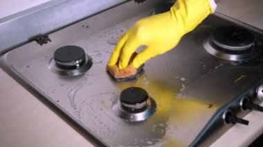 Lastik eldiven, kirli gaz sobasını süngerle yıkar. Oda servisi kavramı.