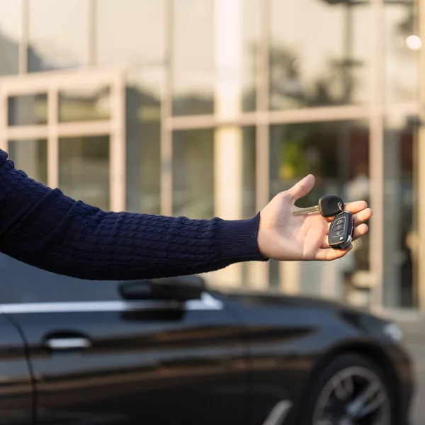 Mano con llaves de un coche de lujo en el fondo de la sala de exposición — Foto de Stock