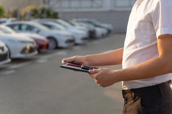 Gerente de ventas con portapapeles y llave del coche, en el fondo del parque de automóviles. Concesionario de alquiler, alquiler de coches . — Foto de Stock