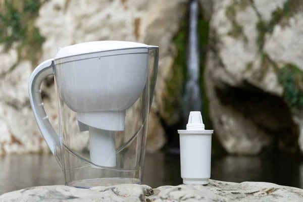 Waterfilterkruik met filter, huishoudelijke waterzuiveraar op de achtergrond van de natuur — Stockfoto