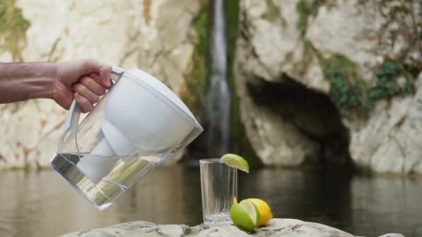 男性の手は ガラスに水濾過治具から明確な濾過水を注ぎます — ストック動画