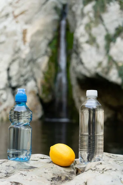 Bir dağ deresinin arka planında mineral doğal içme suyu olan iki plastik şişe. — Stok fotoğraf