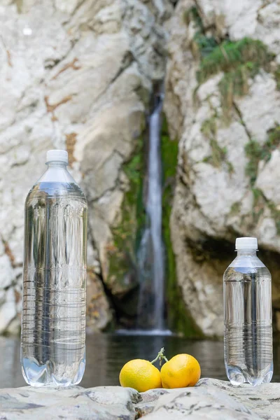 Imagen de agua mineral embotellada con sabor cítrico sobre el fondo de una cascada en los Alpes — Foto de Stock