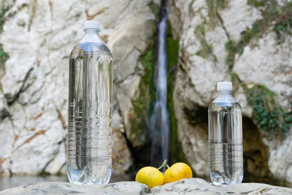 Dos botellas con sabor a mandarina en el fondo de la cascada. Imágenes de agua embotellada — Foto de Stock