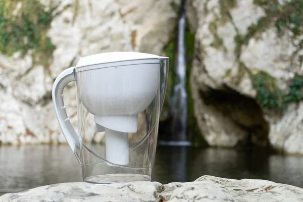 Water filter jugs on the background of a mountain waterfall or river