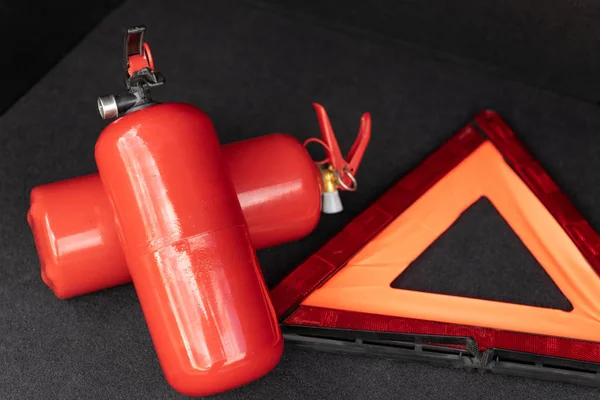 Zestaw narzędzi awaryjnych pojazdu, czerwony trójkąt ostrzegawczy i gaśnica w bagażniku samochodu. Elementy niezbędne dla samochodu osobowego — Zdjęcie stockowe