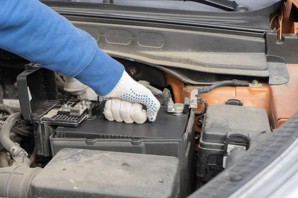 Um mecânico de carro substitui uma bateria. Carro de manutenção — Fotografia de Stock