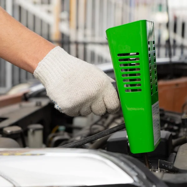 Homem a verificar a bateria do carro. verificar o nível da bateria do carro com um garfo de carga — Fotografia de Stock