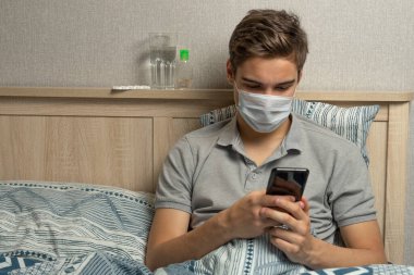 Grip veya koronavirüsü olan bir hasta telefonu karantina sırasında kullanır. Covid-19 salgını .