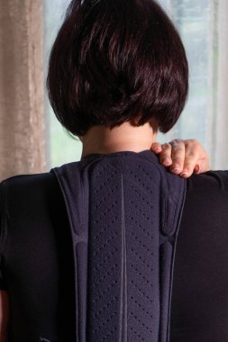 Penceredeki kız beline ortopedik korse takıyor.