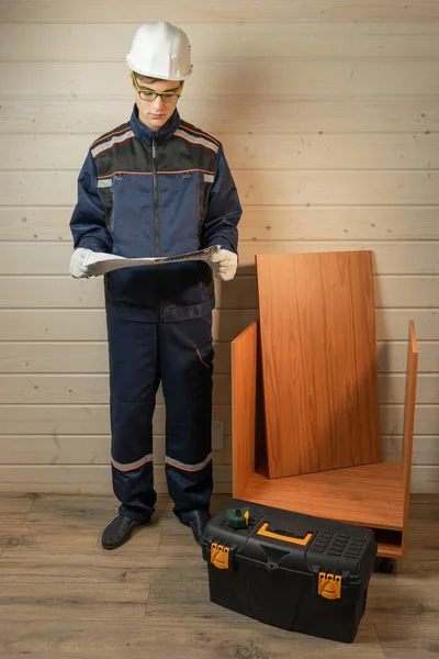 Furniture repair and assembly concept. Young man assembling furniture with instruction manual