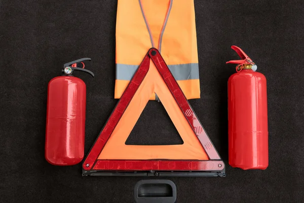 Elements of the essentials for a passenger car: manual fire extinguisher, folding emergency automobile traffic warning stop sign, high-visibility vest