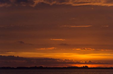 Chascomus Gölü üzerinde gün batımı, turuncu bulutlu gökyüzü.