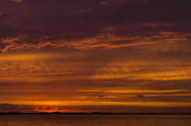 Chascomus Gölü üzerinde gün batımı, turuncu güzel bulutlu gökyüzü