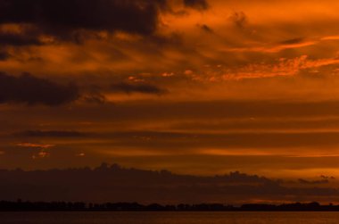 Chascomus Gölü üzerinde gün batımı, turuncu güzel bulutlu gökyüzü