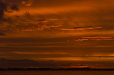 Chascomus Gölü üzerinde gün batımı, turuncu güzel bulutlu gökyüzü