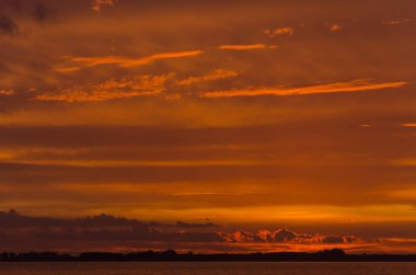 Chascomus Gölü üzerinde gün batımı, turuncu güzel bulutlu gökyüzü