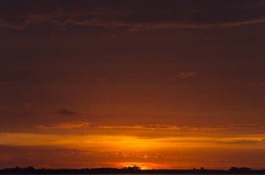 Chascomus Gölü üzerinde gün batımı, turuncu bulutlu gökyüzü.