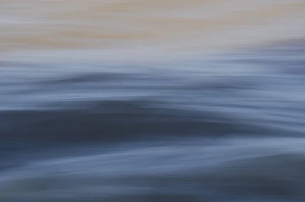 Textura de água em movimento rápido, em tons cinza e amarelado . — Fotografia de Stock