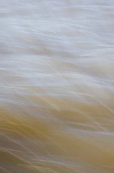 Textura de água em movimento rápido, em tons suaves amarelados . — Fotografia de Stock