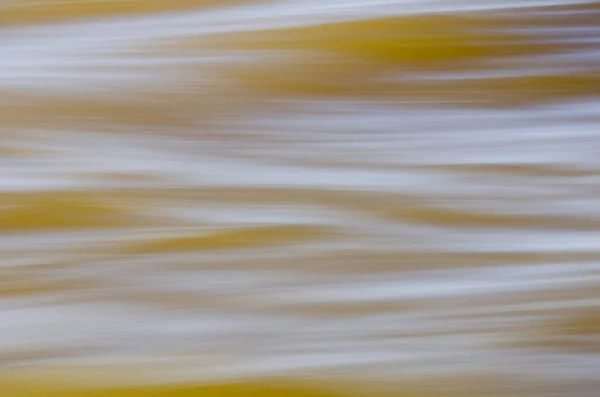 Textura de água em movimento rápido, em tons amarelados . — Fotografia de Stock