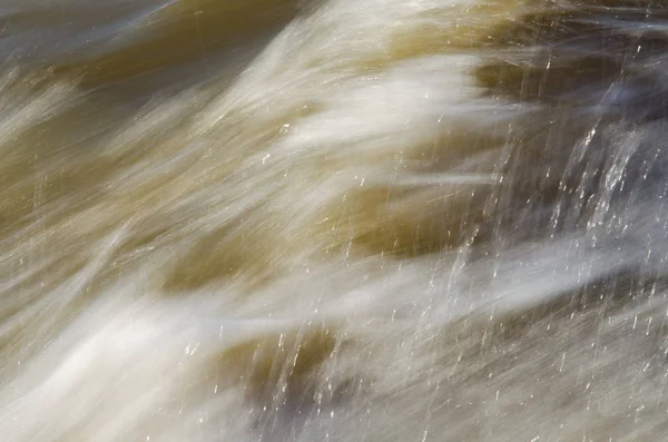 Textura de agua en movimiento rápido, en tonos amarillentos . —  Fotos de Stock