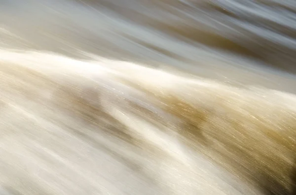 Textura de agua en movimiento rápido, en tonos suaves amarillentos . —  Fotos de Stock