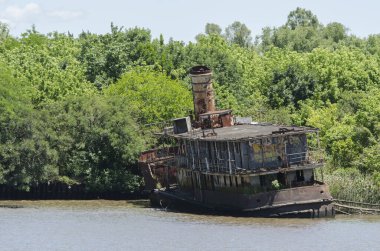 Eski gemi terk edilmiş ve bir su kanalının kıyısında paslanmış.
