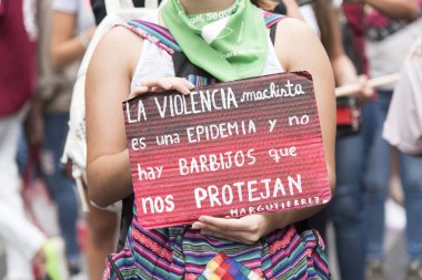 CABA, Buenos Aires / Argentina; March 9, 2020: international women's day. A woman with a green scarf holds a sign: sexist violence is an epidemic and there are no mask covers that protect us