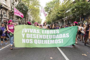 CABA, Buenos Aires / Argentina; March 9, 2020: international women's day. A group of women marching holding a banner with a message: Live, free and indebted we want to be!