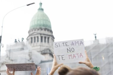 Caba, Buenos Aires / Arjantin; 9 Mart 2020: Uluslararası Kadınlar Günü. Ulusal Kongre 'nin önünde cinsiyet şiddetine karşı bir poster tutan eller: Eğer sizi seviyorsa sizi öldürmez.