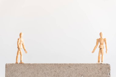 Sosyal uzaklık sembolü: iki ahşap insan figürü arasında iyi bir ayrılık bulunan beton bir blokta duruyor..