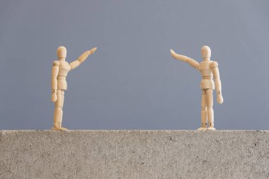 Coronavirüs salgını nedeniyle zorunlu olan sosyal mesafeler, covid-19. Bir çift tahta insan figürü birbirlerine güvenli bir mesafeden el sallıyorlar..