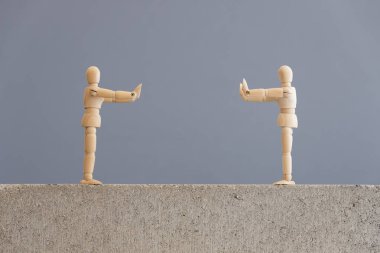 Coronavirüs salgını nedeniyle zorunlu olan sosyal mesafeler, covid-19. Birbirlerinden güvenli mesafede duran bir çift tahta insan figürü..