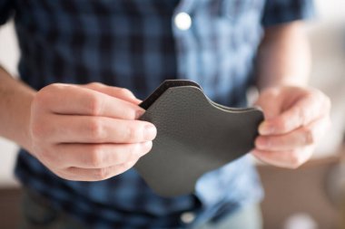 Koronavirüs salgını bağlamında ev yapımı koruyucu bir maskenin parçası olacak sentetik deri parçalarını tutan eller..