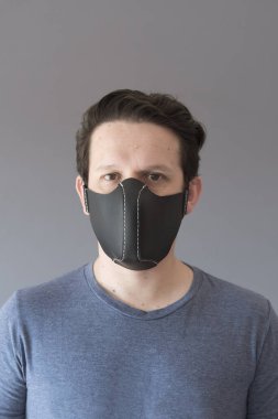 Coronavirus hastalığının yayılmasını önlemek için ev yapımı sentetik deri koruyucu maske takan genç bir adamın portresi..