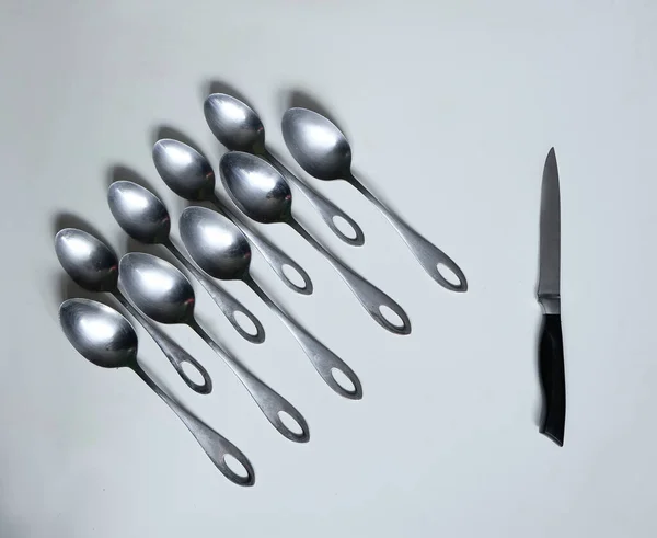 Beyaz bir masada metal kaşıklar ve bıçak.