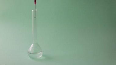 Eldivenli el kimyageri test tüpünden sıvı karıştırıyor. Mavi arkaplan.