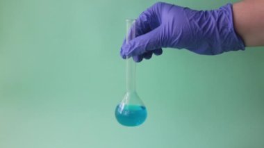 Bilim adamı mavi renkli sıvıyı test tüpüne döküyor. Mavi arka planda karıştırılan sıvılar. 